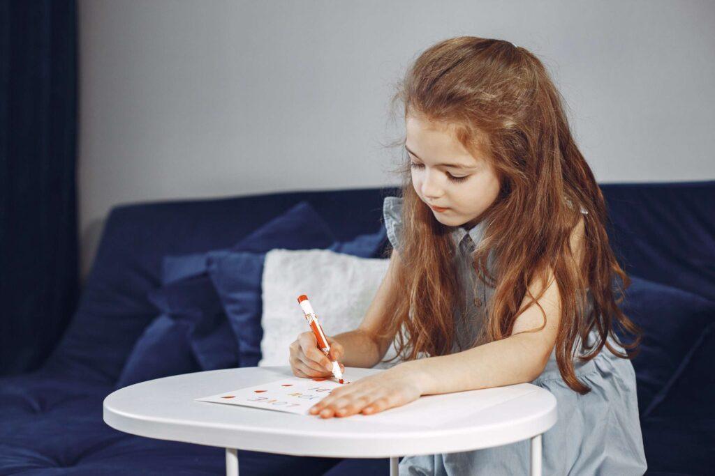 Dlaczego karty pracy są ważne dla dzieci? karty pracy Girl-sitting-couch-blue-sofa-child-draws-scaled