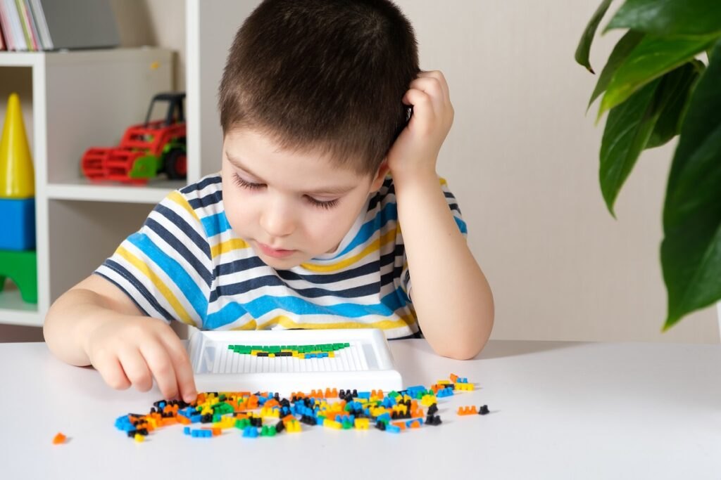 Rozwój zdolności motorycznych u dzieci: gry rozwijające zdolności motoryczne rąk Boy-4-years-old-plays-with-mosaic-collects-picture-from-small-plastic-parts-development-fine-motor-skills-children