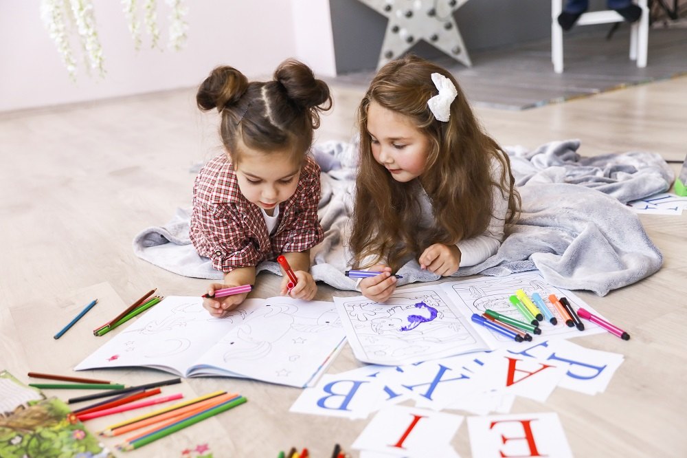 Nauka alfabetu i literek nauka alfabetu,alfabet Two-tiny-cute-girls-which-are-drawing-coloring-book-laying-floor-blanket-learning-letters