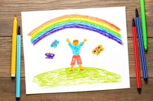 Co oznaczają szczegóły rysunku dziecka: kolory, rozmiar, proporcje i postacie na rysunku Boy-rejoices-rainbow-children-s-drawing-white-paper-wooden-table-with-markers