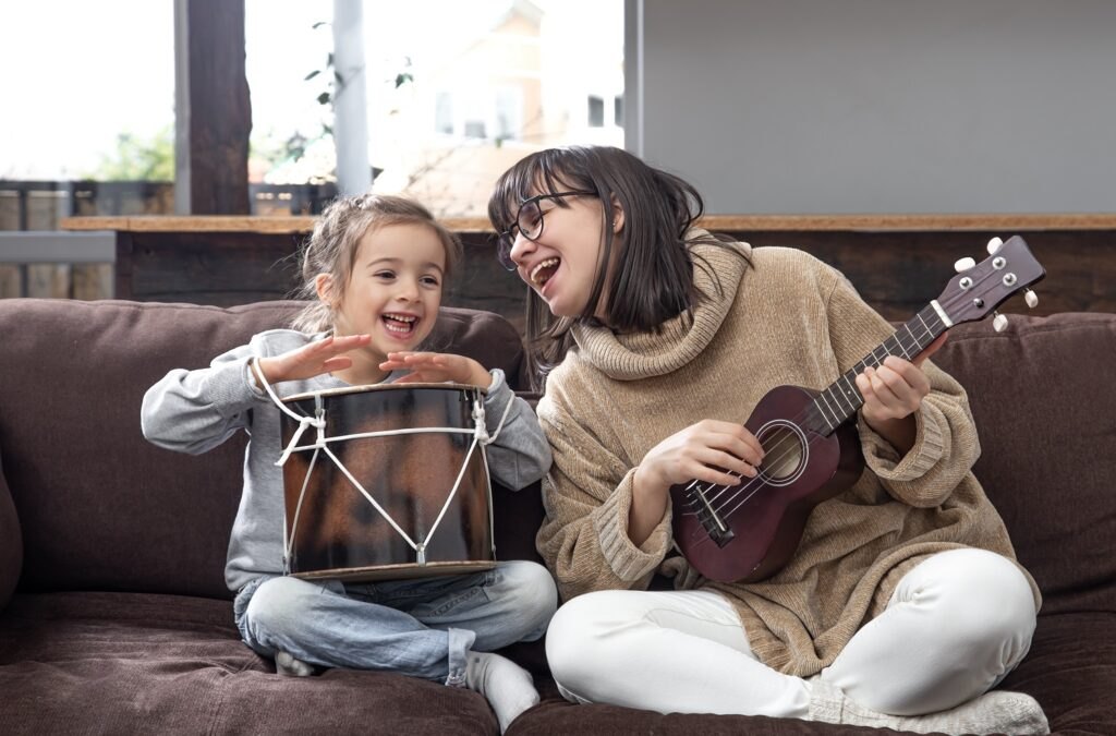 Wpływ muzyki na rozwój dzieci Mom-plays-with-her-daughter-home-lessons-musical-instrument-children-s-development-family-values-concept-children-s-friendship-family